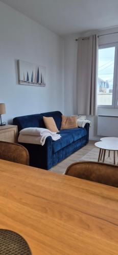a living room with a blue couch and a table at Appartement coquet proche plage in Berck-sur-Mer