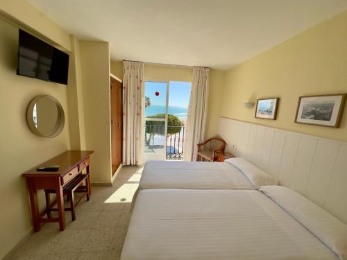 a hotel room with two beds and a table with a mirror at Hotel Cabello in Torremolinos