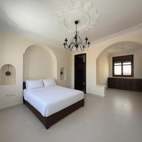 a bedroom with a large white bed and a chandelier at Villa Adan in Sidi Salah