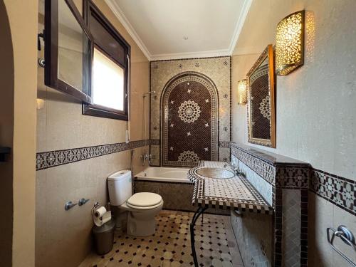 a bathroom with a toilet and a tub and a sink at Villa Adan in Sidi Salah