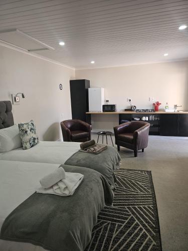 ein Schlafzimmer mit zwei Betten und zwei Stühlen in der Unterkunft Clanwilliam Accommodation in Clanwilliam