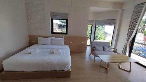 a bedroom with a large white bed and a table at บ้านฮา พอชเทล Baan Ha Poshtel in Nan