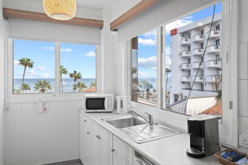 a kitchen with a sink and windows with a view of the ocean at Larnaca Bay Suites in Larnaca