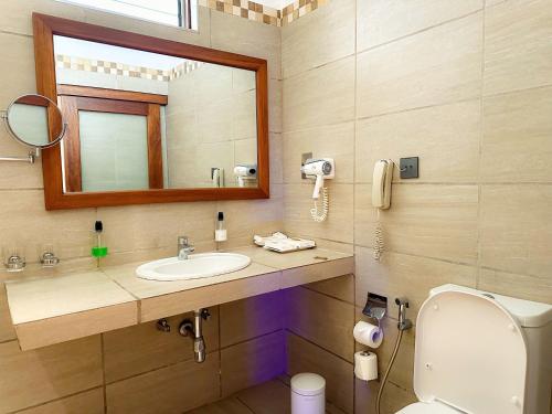 a bathroom with a sink and a mirror and a toilet at Travellers Beach Hotel & SPA in Mombasa