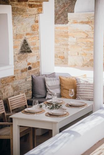 a white table with plates and wine glasses on it at Ios Pearls-2 houses in Mylopotas