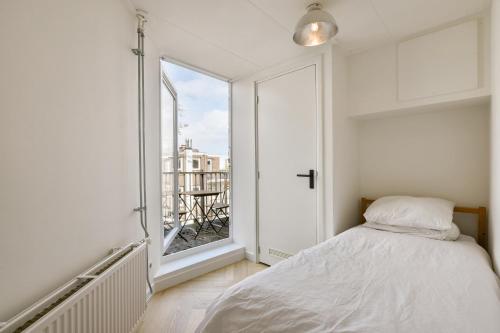 a white bedroom with a bed and a large window at Bright City Retreat near Center & RAI in Amsterdam