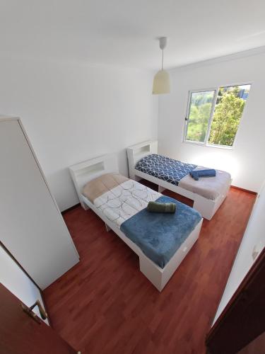 two beds in a room with two windows at Eiras AL Ilha da Madeira in Santa Cruz
