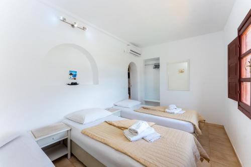 two beds in a room with white walls at Birds Villa Apartments with Heated Pool - Including Car and Breakfast in Perissa