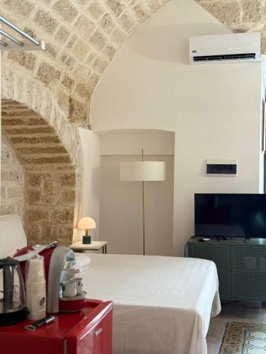 a bedroom with a white bed and a brick wall at La Baita nel Borgo HOWME in Bari