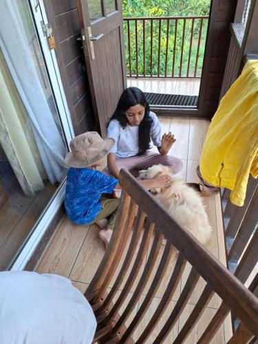 a woman and two children sitting on a porch with a dog at APKA ECOvillage in Trichūr