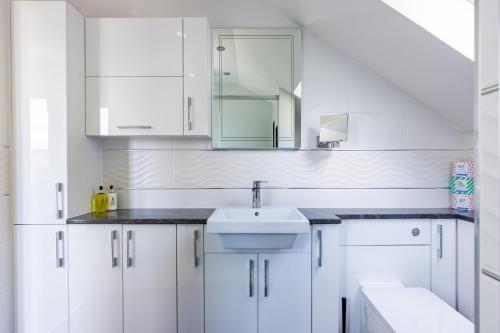 a white bathroom with a sink and a mirror at Fern View in Inverness