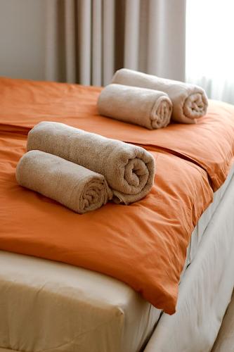 three rolled towels sitting on top of a bed at Not A Hotel Cesis in Cēsis