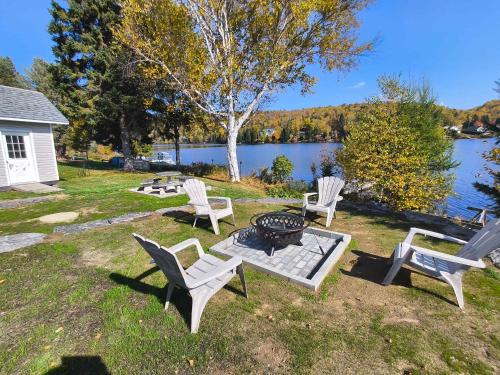 a group of chairs and a fire pit next to a lake at Waterfront with Spa - Etoile Filante in Saint Zenon
