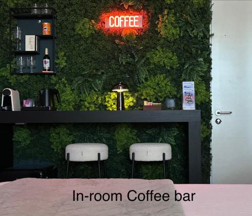 Eine Bar mit zwei Barhockern vor einer grünen Wand in der Unterkunft Hotel chic room in Heerlen