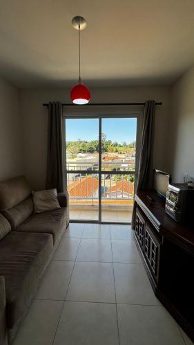 a living room with a couch and a large window at Apartamento Melbela IV AP 41 in Espirito Santo Do Pinhal