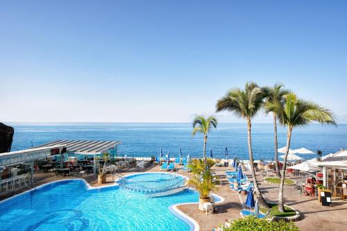 a pool with palm trees and the ocean in the background at Bahia Blanca in Puerto Rico de Gran Canaria