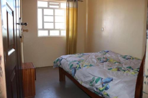 ein Schlafzimmer mit einem Bett, einem Fenster und einer Tür in der Unterkunft Zeph Bnb in Nairobi