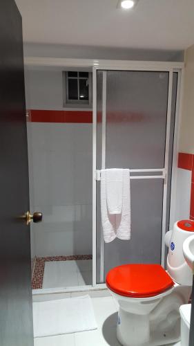 La salle de bains est pourvue d'une douche et de toilettes rouges. dans l'établissement Apartamentos Turisticos Buena Vista, à San Andrés