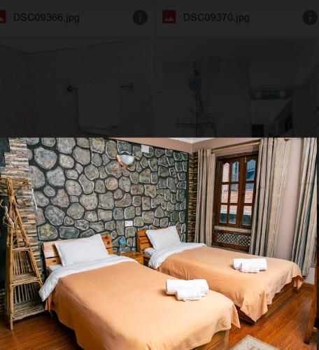 two beds in a room with a stone wall at City Guest House in Bhaktapur