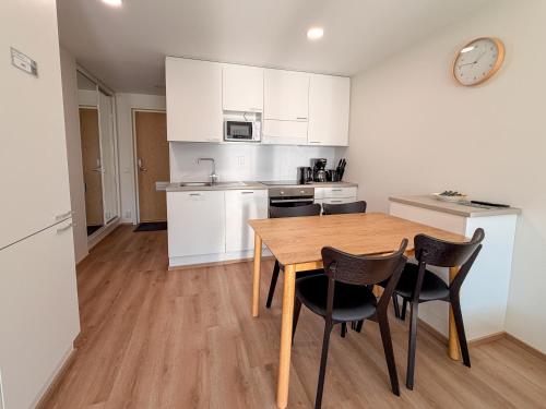 a kitchen with white cabinets and a wooden table and chairs at Lumi Glow Apartments in Rovaniemi