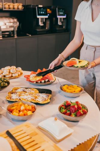a woman holding plates of food on a table at Dunetton - self check-in hotel in Klaipėda