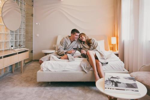 a man and a woman sitting on a bed at Dunetton - self check-in hotel in Klaipėda