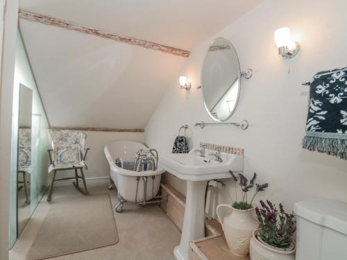 a bathroom with a sink and a tub and a mirror at 7 The Cedars in Wotton-under-Edge