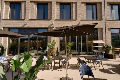 a patio with tables and chairs and an umbrella at Hotel ROMY by AMANO in Berlin