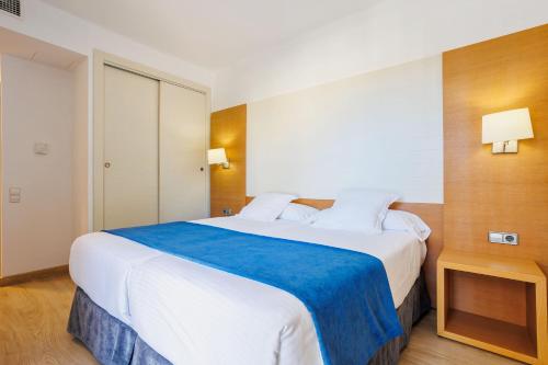 ein Schlafzimmer mit einem großen weißen Bett und einer blauen Decke in der Unterkunft Hotel Morlans in Paguera