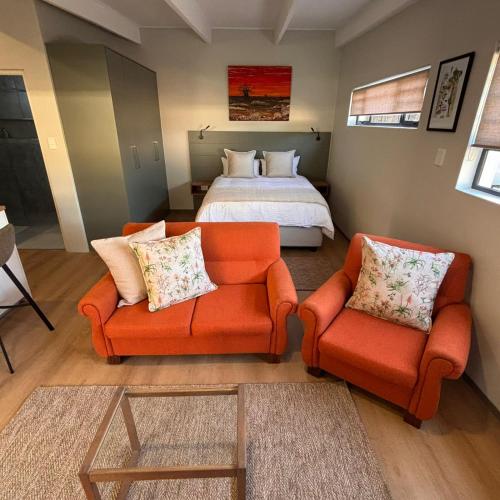 a bedroom with a bed and two orange chairs at Bonnie Doon Luxury Studio in Bunkers Hill