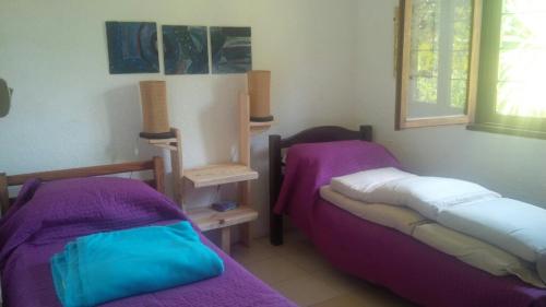 アグアス・ドゥルセスにあるLas Palmerasの紫のシーツが備わる客室内のベッド2台