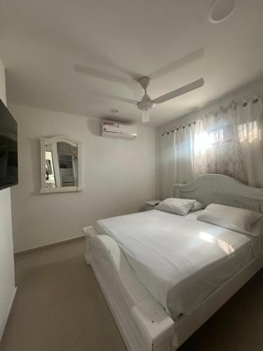 a bedroom with a white bed with a ceiling fan at Bien ubicado 3 -habitaciones 3- Aires in Montería