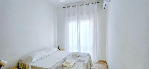 a white bedroom with a bed and a window at Speloncae Apartment in Sperlonga