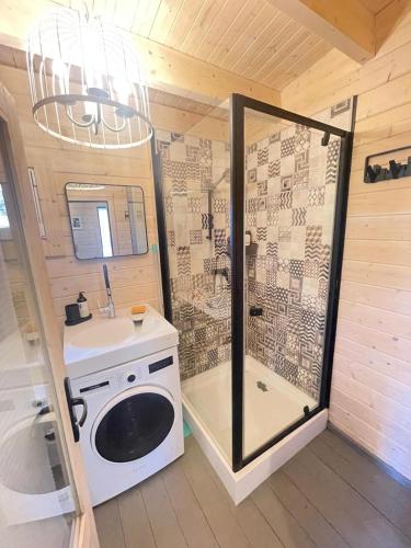 a bathroom with a shower and a washing machine at Māja pie Ziedu laivas in Plieņciems