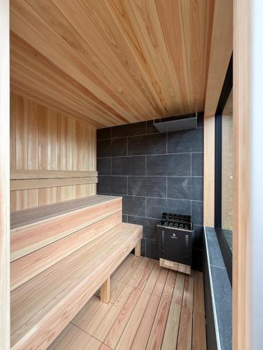 a sauna with a wooden floor and a stove at 海と森と宿 - mina-to - in Futtsu