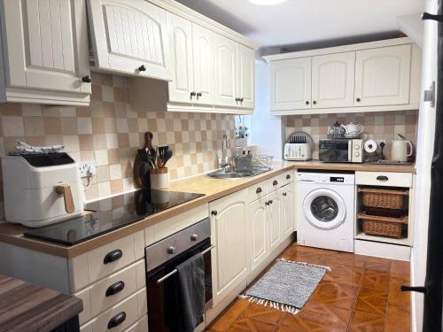 a kitchen with white cabinets and a washer and dryer at Silver Cottage on Yarm High street and the River free parking available in Yarm