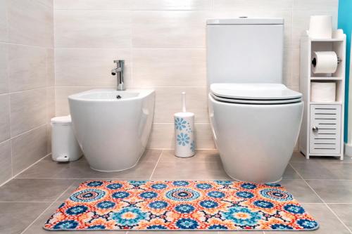 a bathroom with a toilet and a sink and a rug at Domos Ventuno Barumini in Barùmini