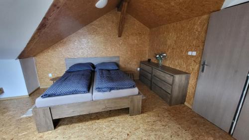 a bedroom with a bed with blue pillows and a dresser at Apartmán u kolejí D in Kašnice