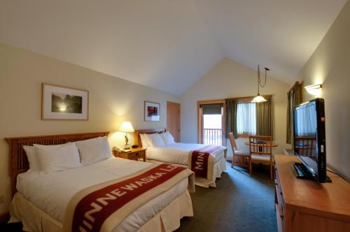 a hotel room with two beds and a flat screen tv at Minnewaska Lodge in Gardiner