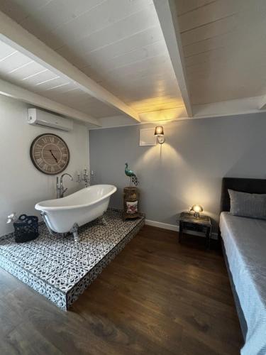 a bathroom with a tub and a clock on the wall at Gémes Vendégház in Vitnyéd