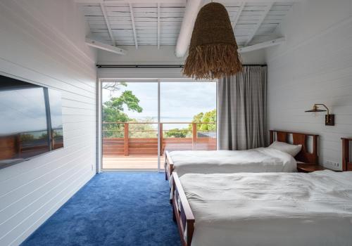 a bedroom with two beds and a balcony at 海と森と宿 - mina-to - in Futtsu
