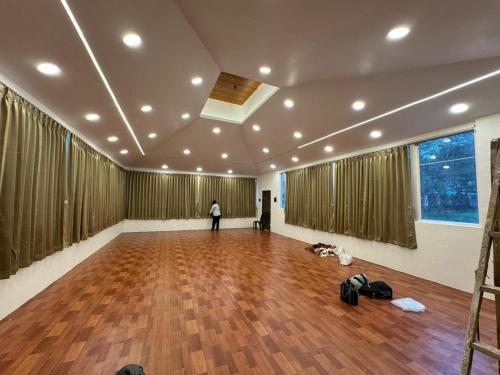 a person standing in a large room with a wooden floor at Harmony Hills Ecostay in Nasrāpur