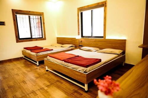 two beds in a room with two windows at Harmony Hills Ecostay in Nasrāpur