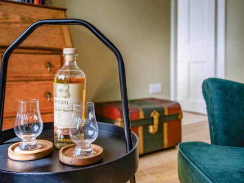 a bottle of alcohol and two glasses on a table at Greenhill in Blackwaterfoot