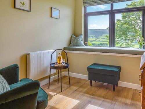 a living room with a chair and a table and a window at Greenhill in Blackwaterfoot