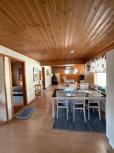 a dining room with a wooden ceiling and a table and chairs at Rauhan pesä in Karigasniemi