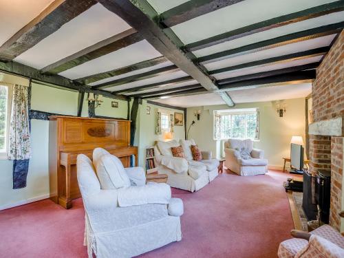 a living room with white chairs and a fireplace at Glebe Cottage in Powick