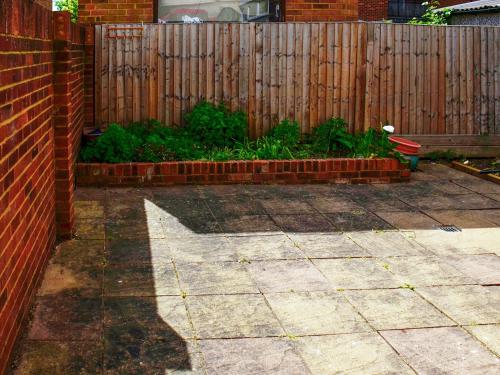 a backyard with a fence and a brick patio at St Mary's Crescent House in Stanwell