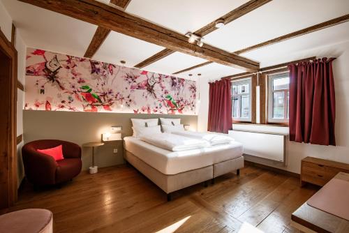 a bedroom with a white bed and a red chair at DAS HOCHREIN in Volkach