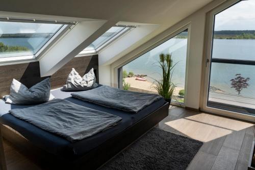 a bedroom with two beds and large windows at Ferienhaus SUNSHINE am Mühlfeldsee in Löbnitz